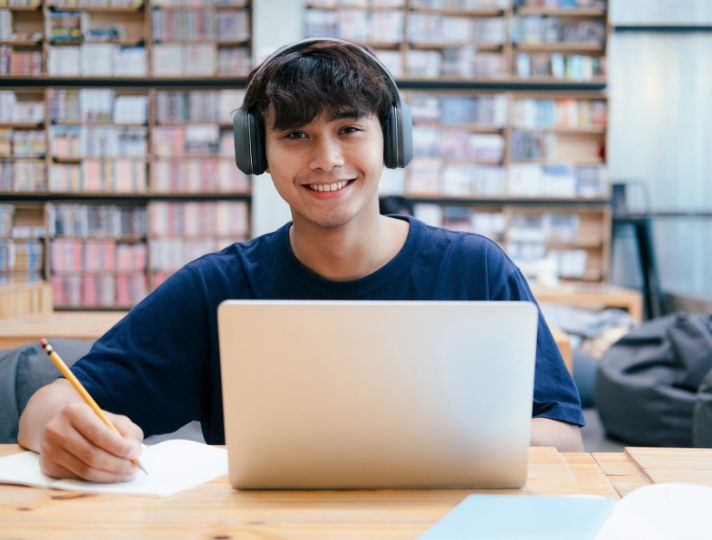 Student smiling whilst working on laptop